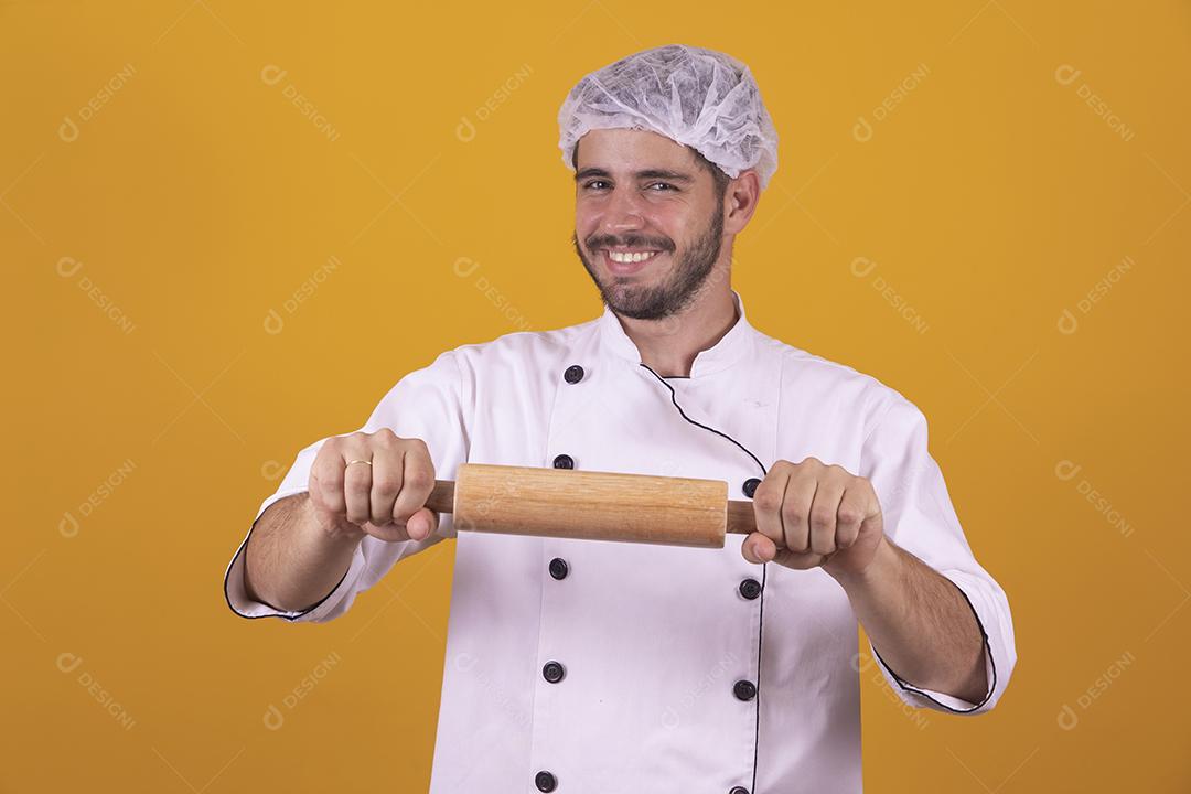 homem chef de cozinha segurando uma esponja de lavar louça e um prato sob fundo amarelo