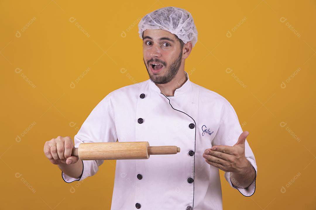 homem chef de cozinha segurando uma esponja de lavar louça e um prato sob fundo amarelo