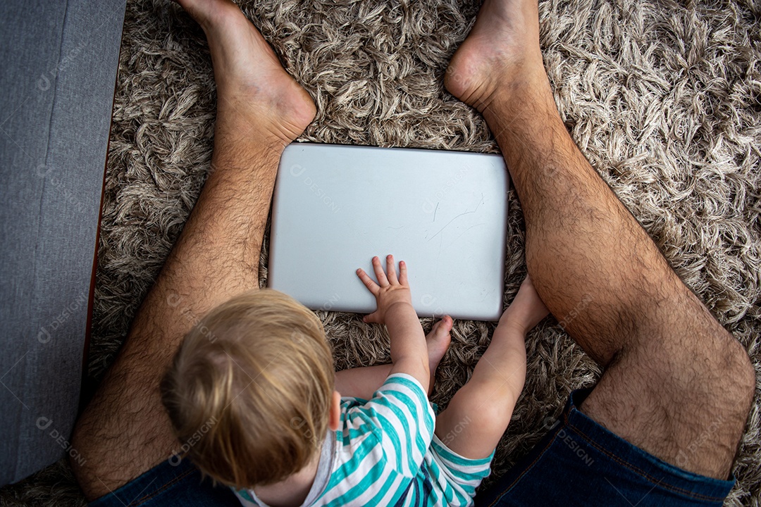 Pai e filho sentados na sala usando tecnologia, laptop, assistindo, brincando ou aprendendo