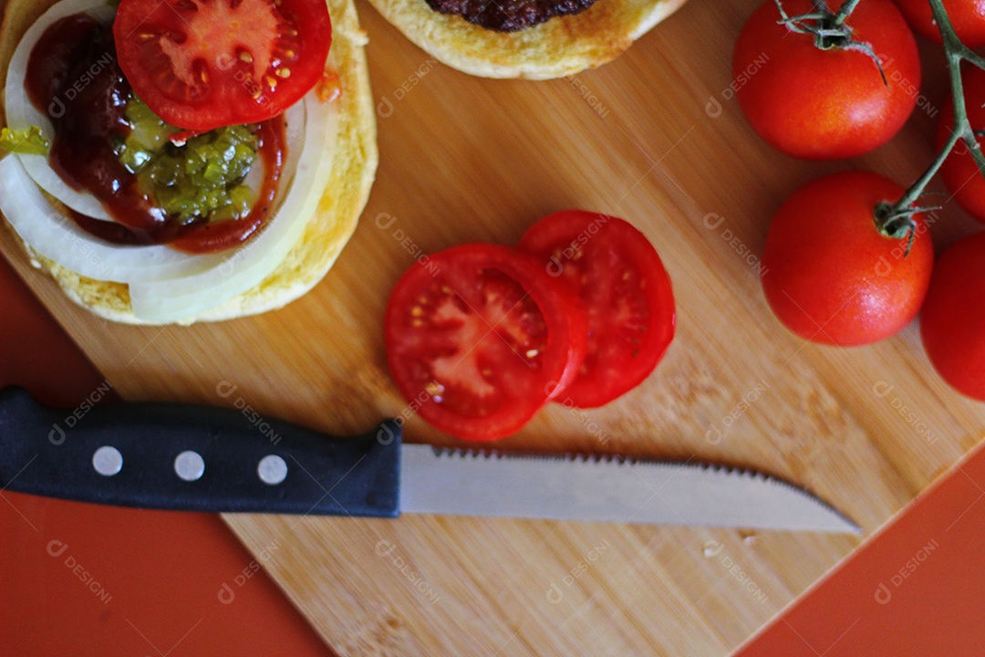 Hambúrgueres estão sendo preparados e servidos em tábuas de madeira, vista superior.