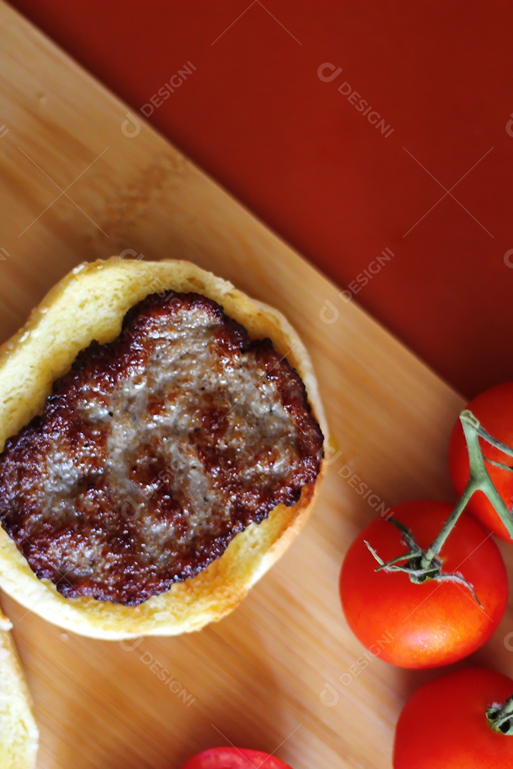 Hambúrgueres estão sendo preparados e servidos em tábuas de madeira, vista superior.