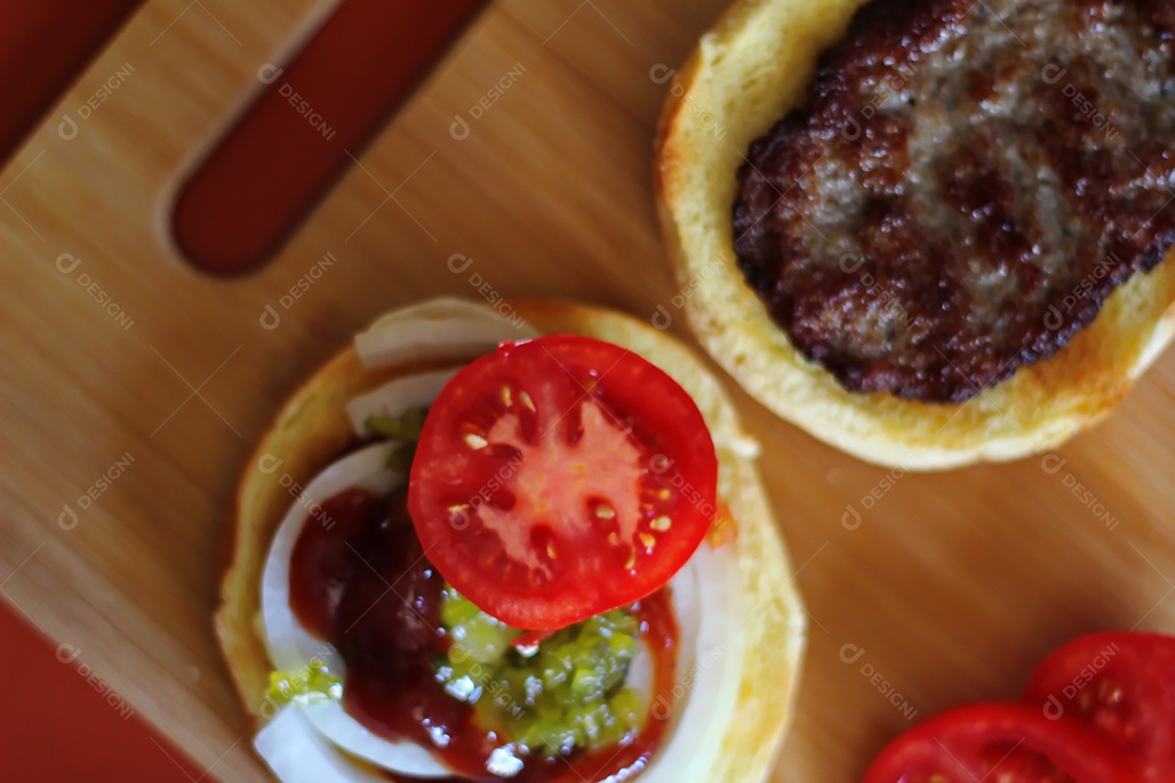Hambúrgueres estão sendo preparados e servidos em tábuas de madeira, vista superior.