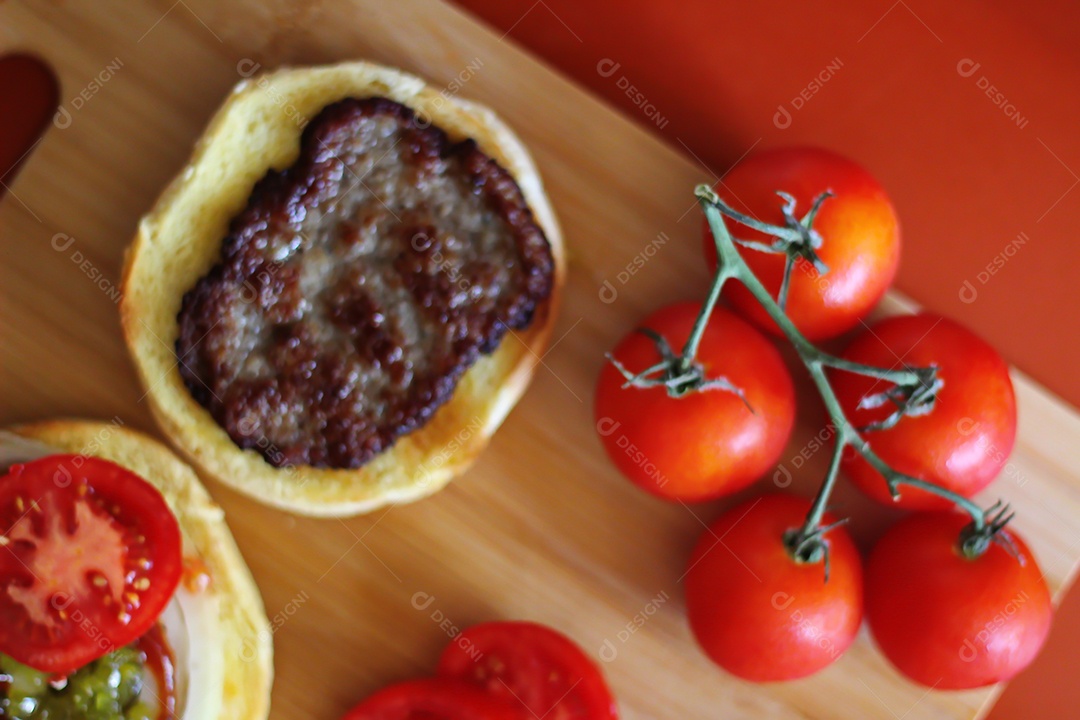Hambúrgueres estão sendo preparados e servidos em tábuas de madeira, vista superior.