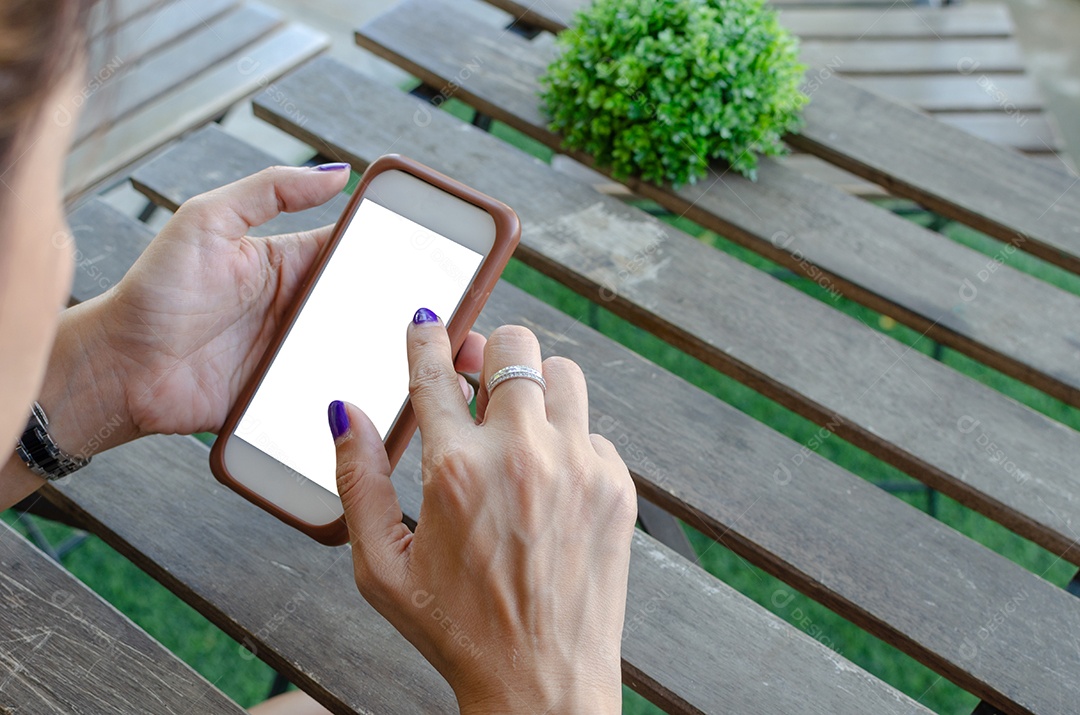 Mulher segurando o telefone inteligente com tela em branco do desktop.