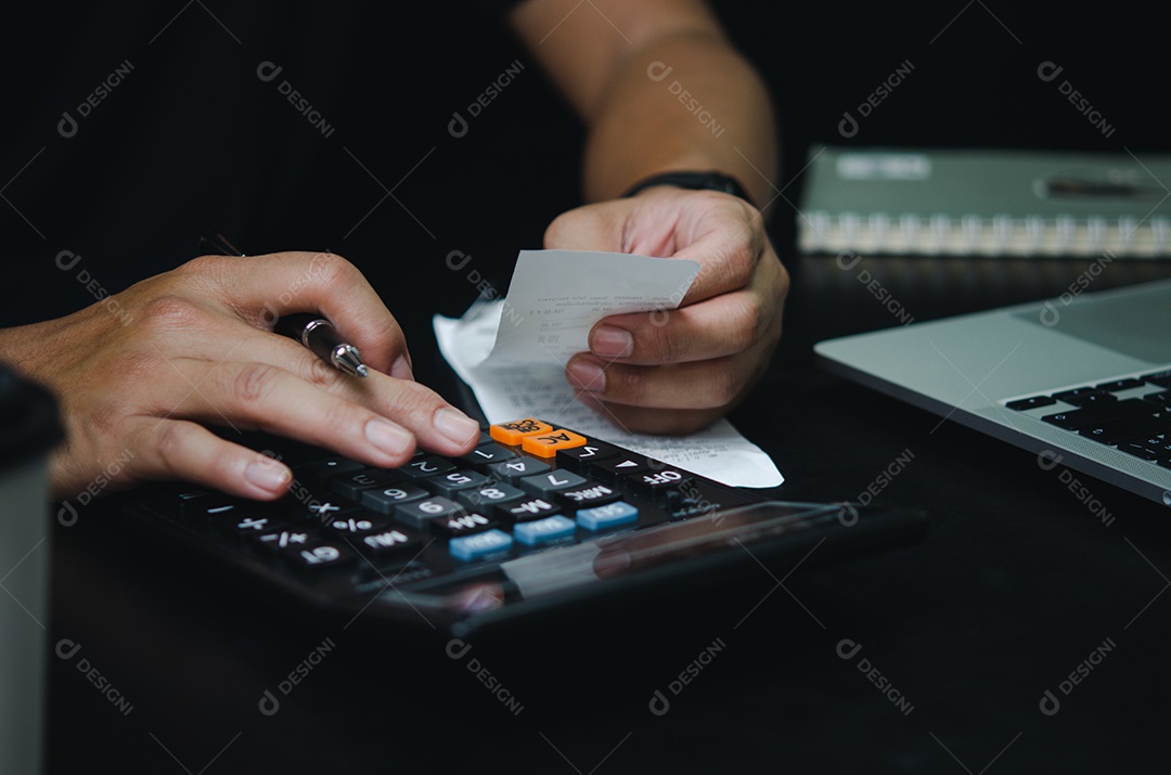 Mão de homem segurando a despesa de caneta e calculadora ou recibo de imposto.