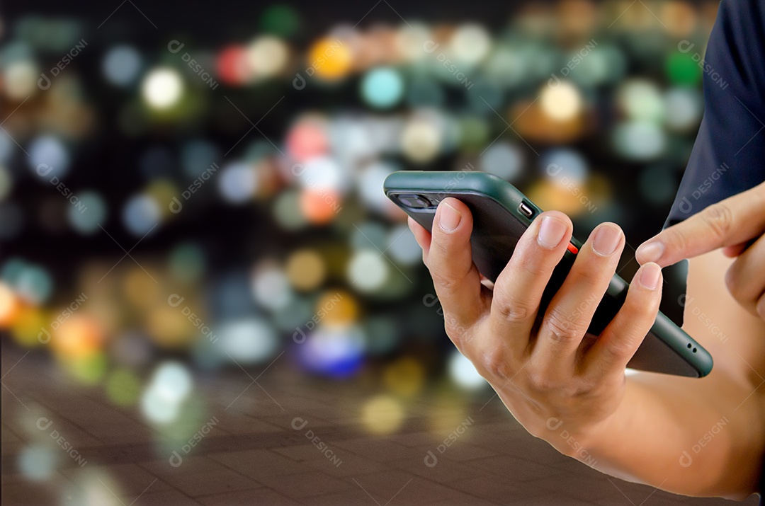 Homem usando celular na rua ao fundo noite