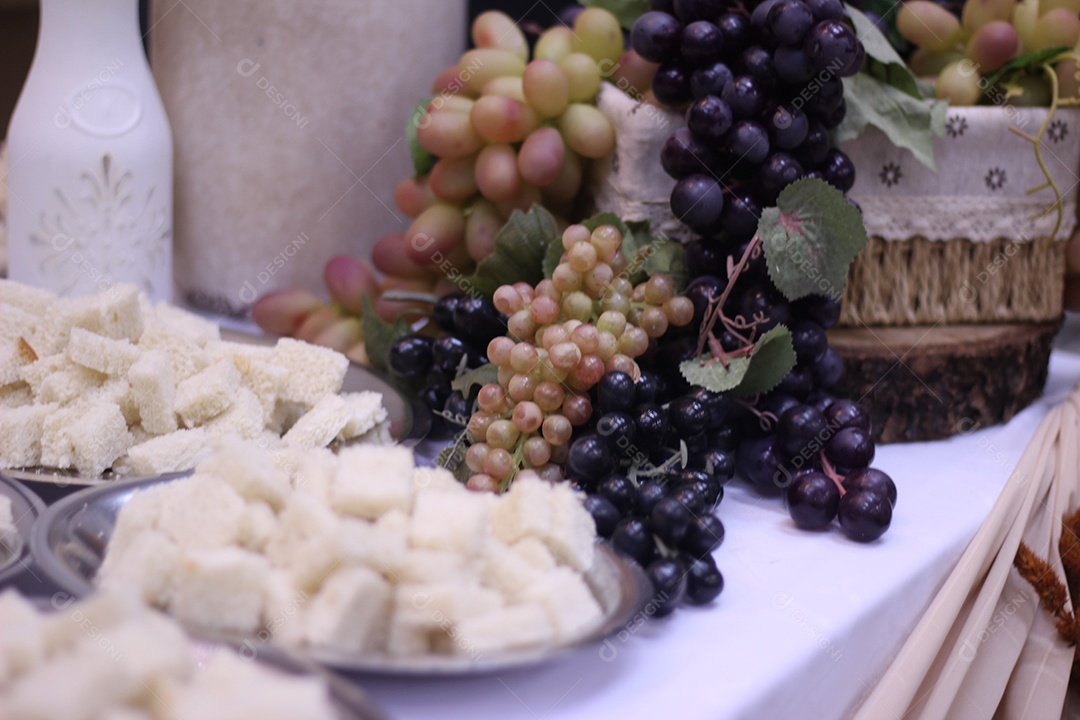 Pães cortados em cubos pequenos para Santa ceia e bandejas para santa ceia com vários cachos de uva ao fundo