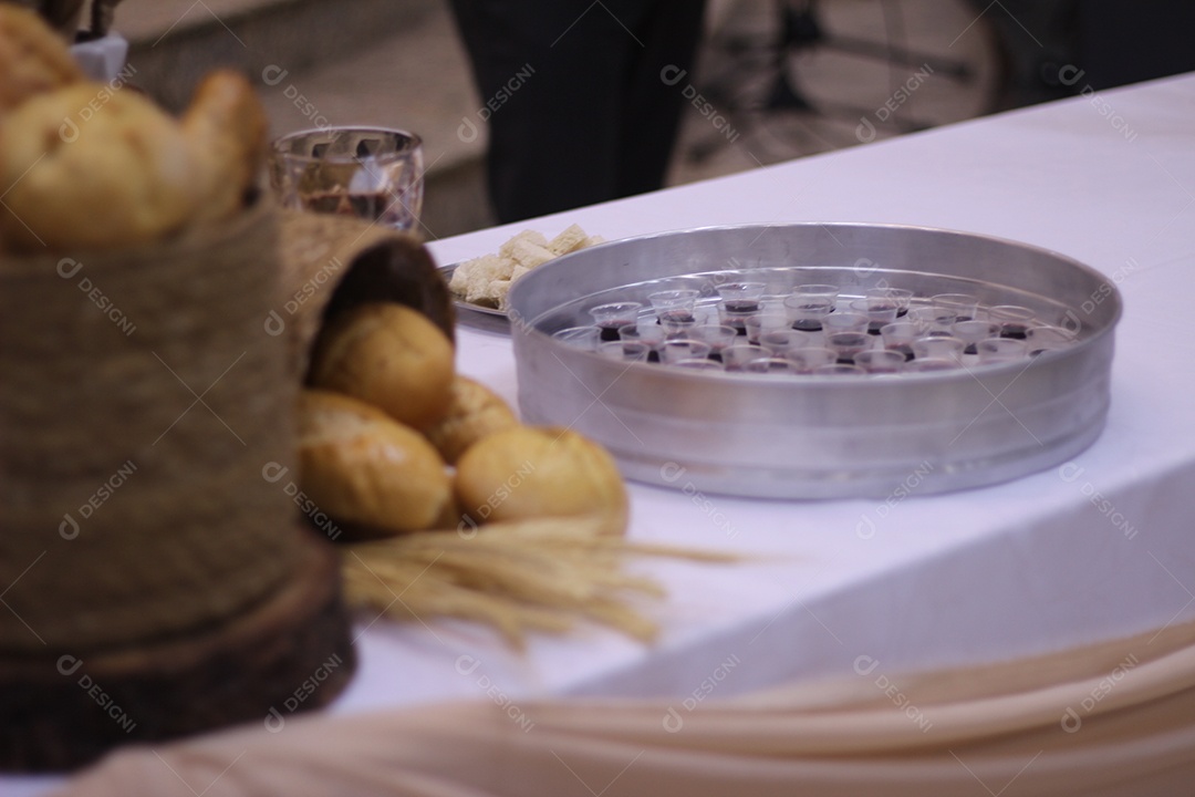 Bandeja para santa ceia com vários copinhos servidos de vinho ao fundo pão