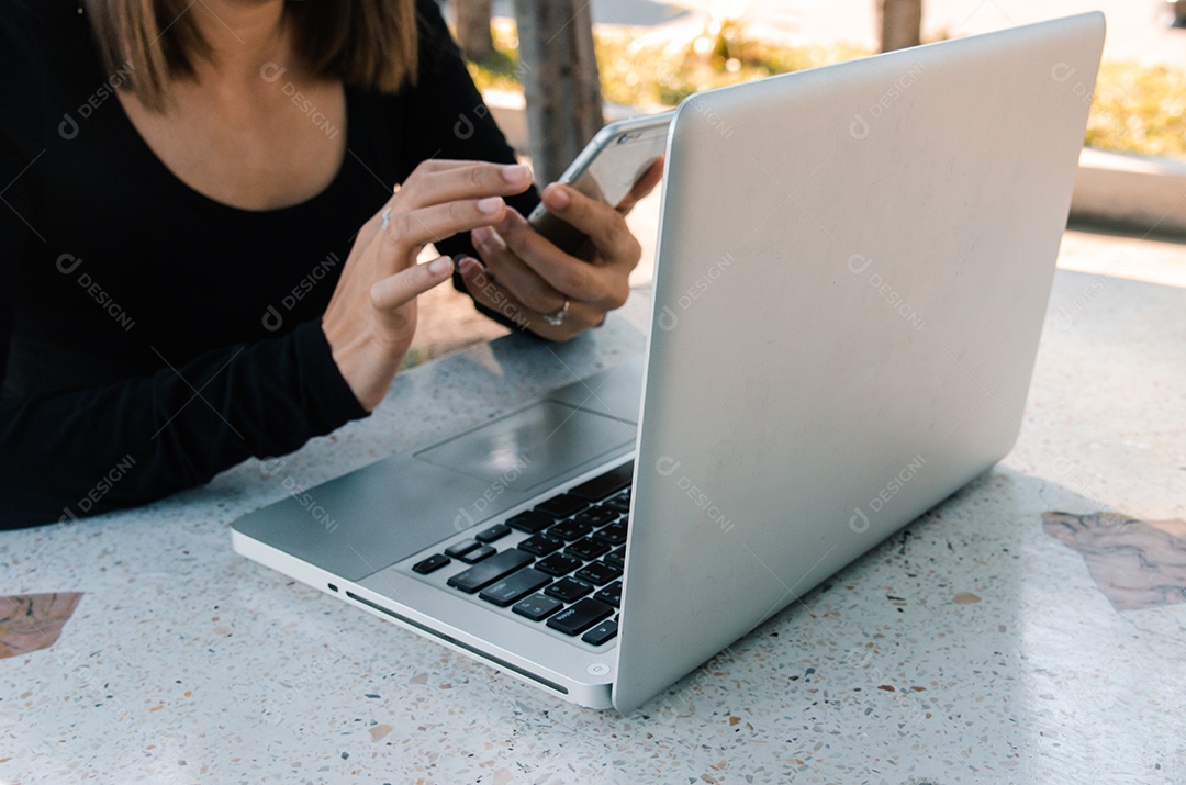 mulher usa smartphone e computador laptop na mesa