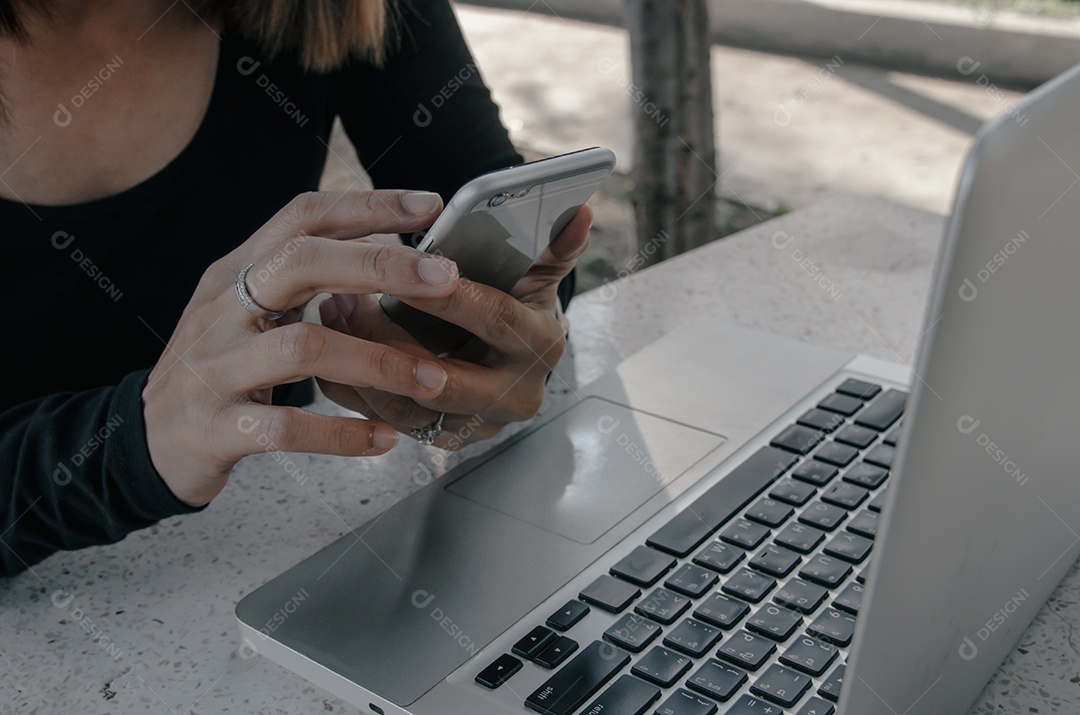 mulher usa smartphone e computador laptop na mesa