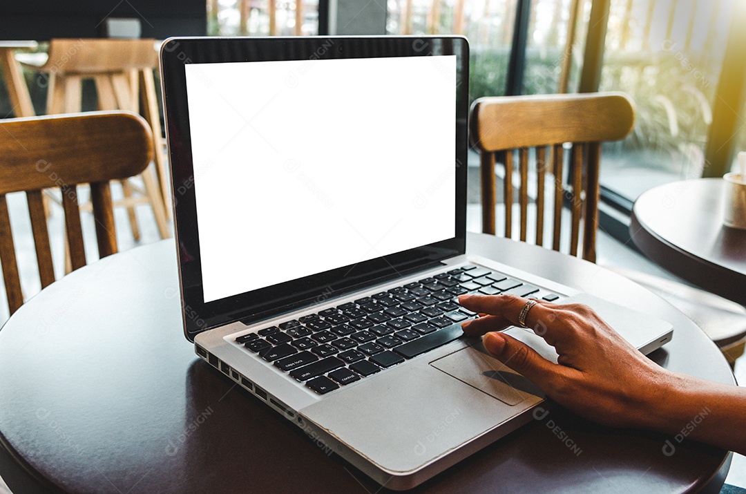 Mãos segurando um cartão de crédito e usando um laptop em cima da mesa