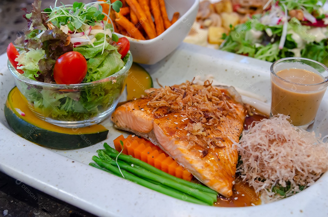 Bife de salmão e salada de legumes em um prato.
