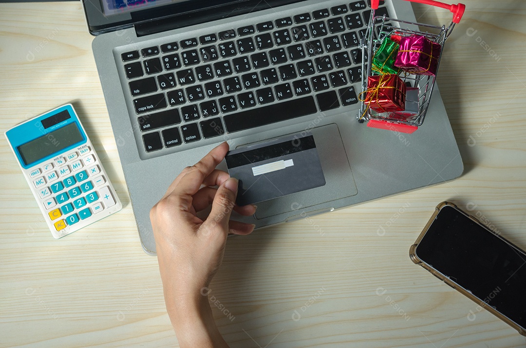 mãos de mulher asiática segurando cartão de crédito e telefone inteligente para compras online em casa.