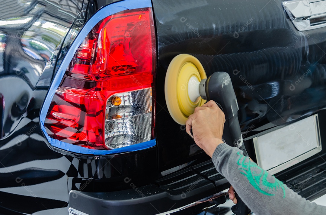 Remova arranhões de carros pretos. Um homem segurando uma ferramenta de polimento de automóveis na garagem