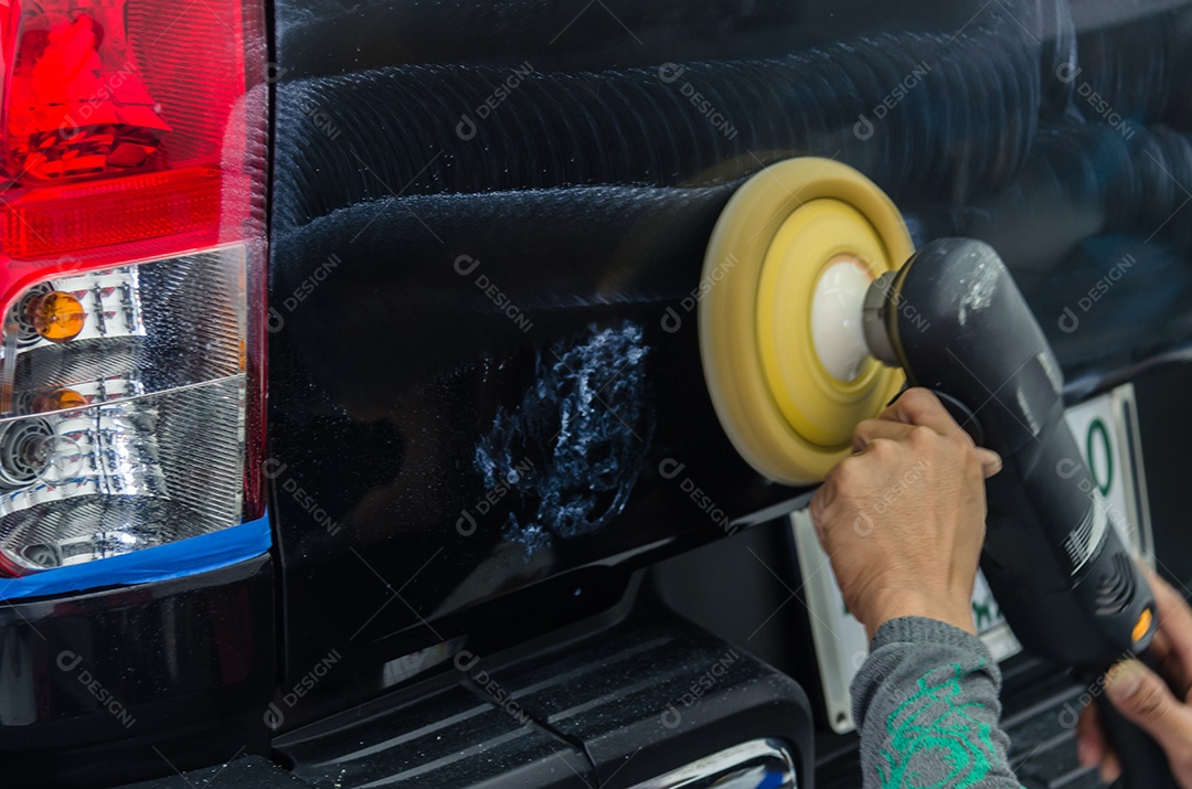 Remova arranhões de carros pretos. Um homem segurando uma ferramenta de polimento de automóveis na garagem