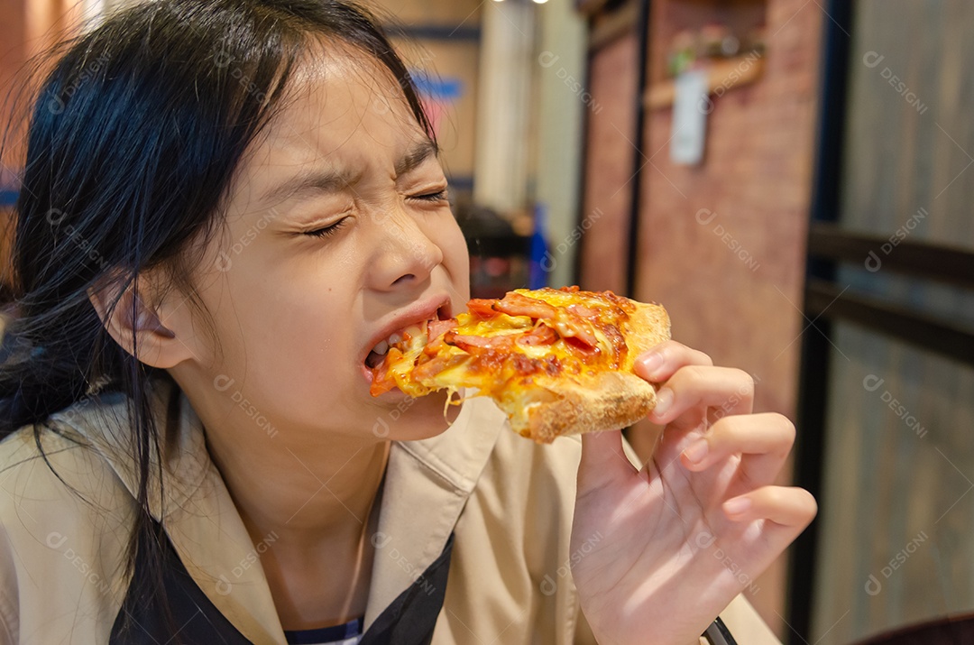 Linda garota asiática comendo pizza no restaurante.