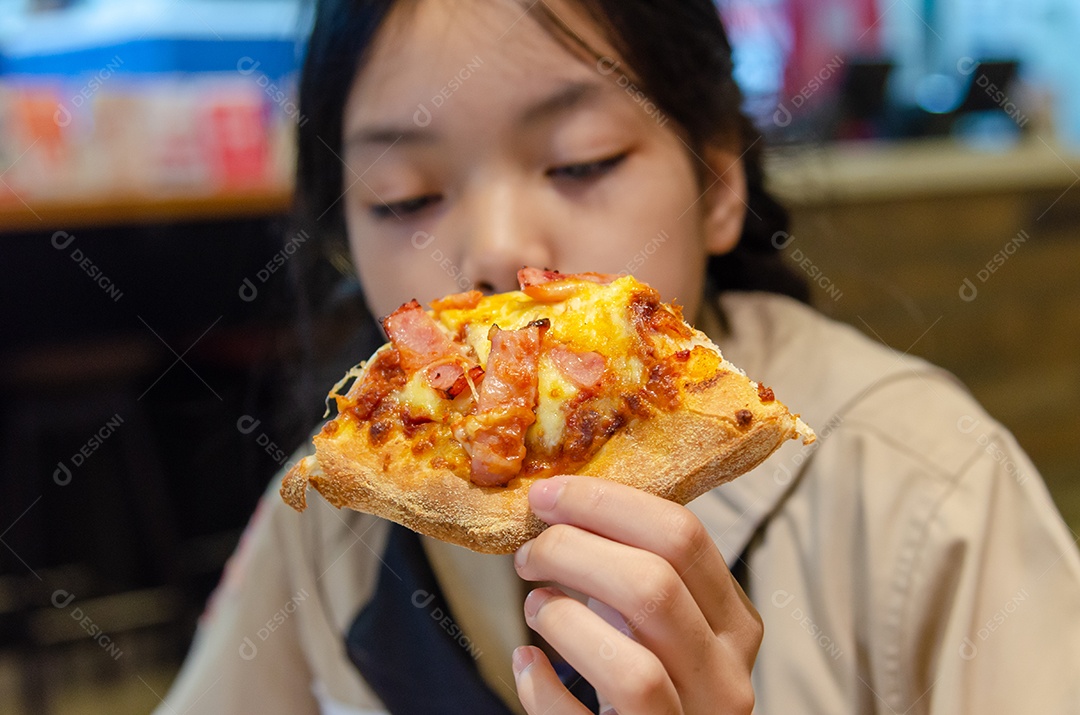 Linda garota asiática comendo pizza no restaurante.