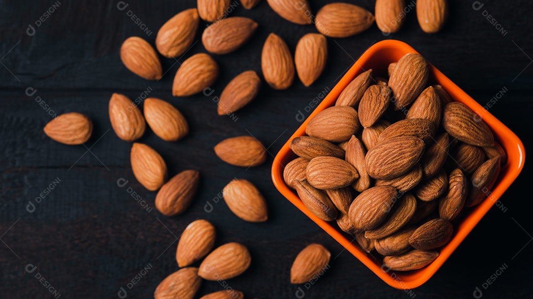 Amêndoas em uma xícara de laranja e colocadas sobre uma velha mesa de madeira