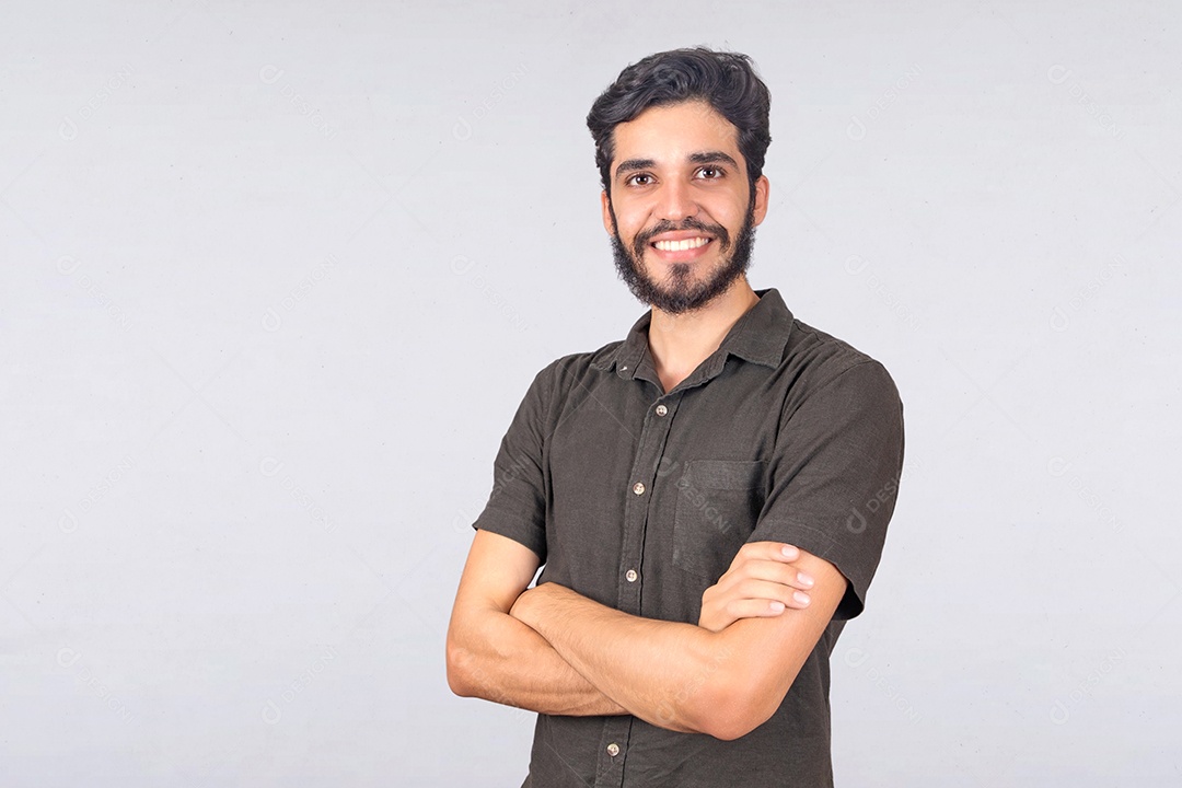 Jovem rapaz sorridente de camiseta cinza com os braços cruzados
