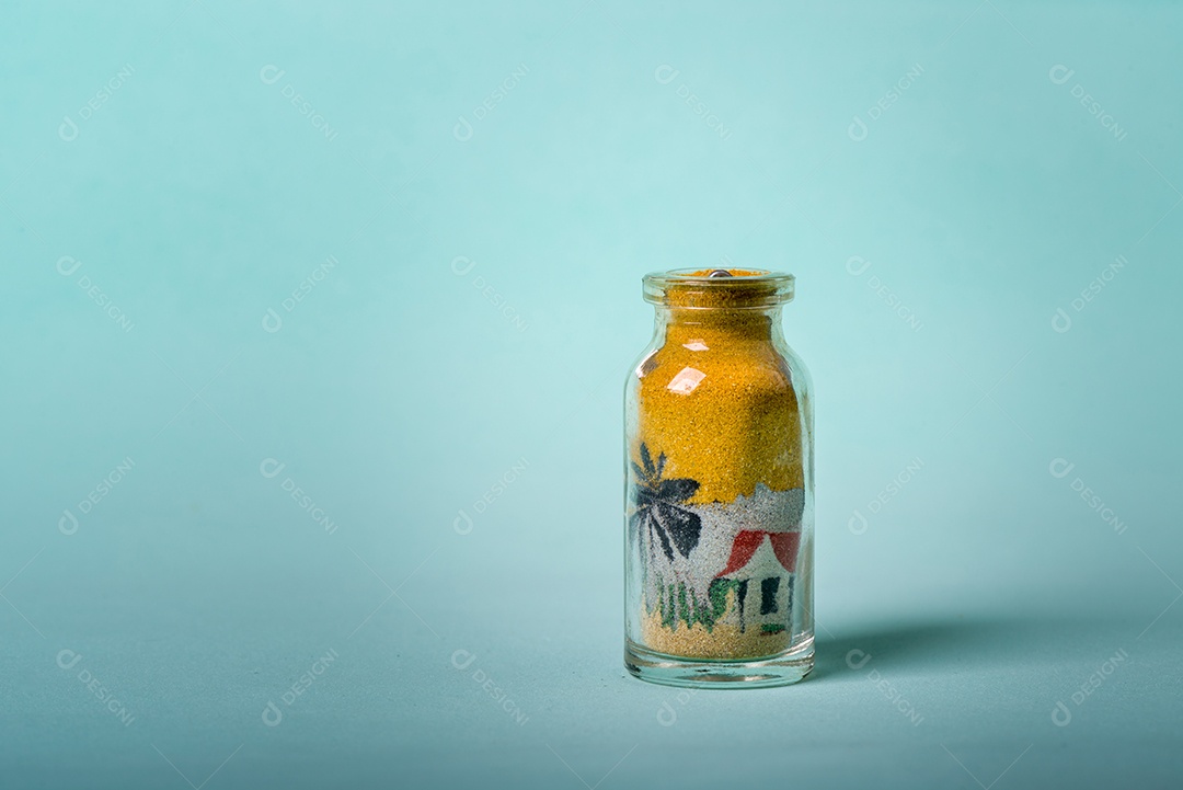 Lembrança artesanal. Garrafa pequena com desenhos feitos com areia colorida, típicos da região nordeste do Brasil em um fundo esverdeado infinito.