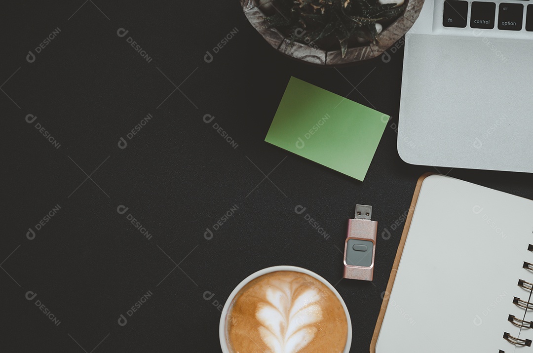 Mesa de escritório com o bloco de notas, café, folha e computador portátil em fundo preto. de vista superior.
