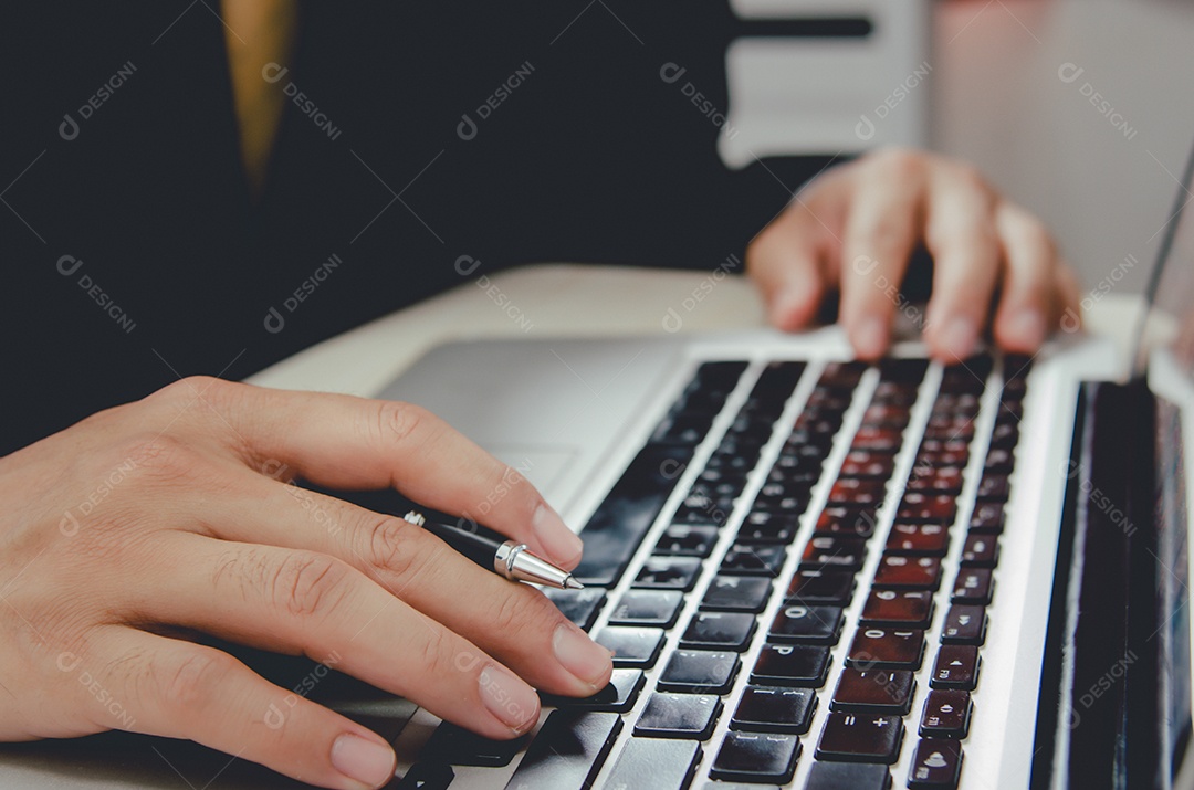 Homem de negócios com uma caneta em um teclado de computador notebook