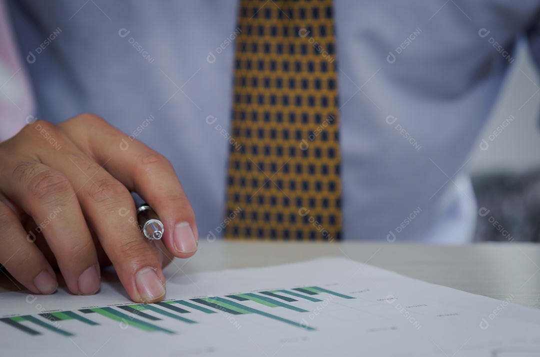 Homem de negócios segurando uma caneta, documentos comerciais, relatórios, gráficos e tabelas de demonstrações financeiras e crescimento do lucro