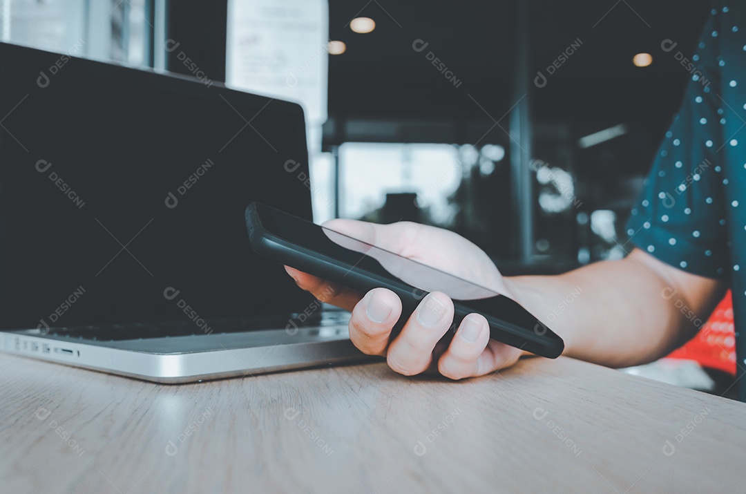 Homem de negócios, segurando um telefone celular, olhando para dados de trabalho e computadores portáteis na mesa do escritório. conceito de negócios e tecnologia