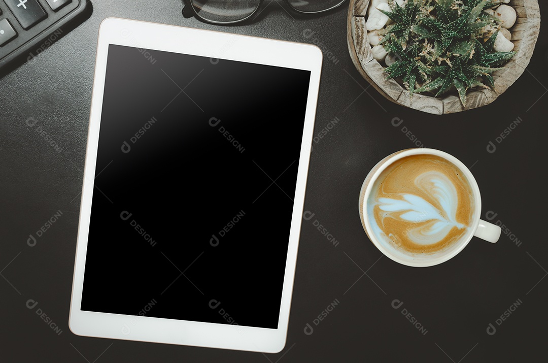 Calculadora e tablet  e xícara de café, cactos na mesa