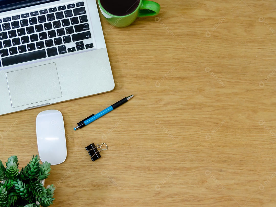 Computador portátil de vista superior, xícara de café, flor e caneta na mesa de madeira.