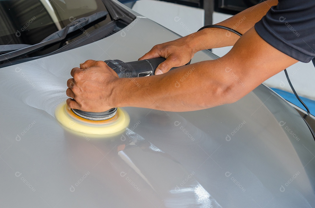 Mãos com polidor de máquina em reparação de automóveis.