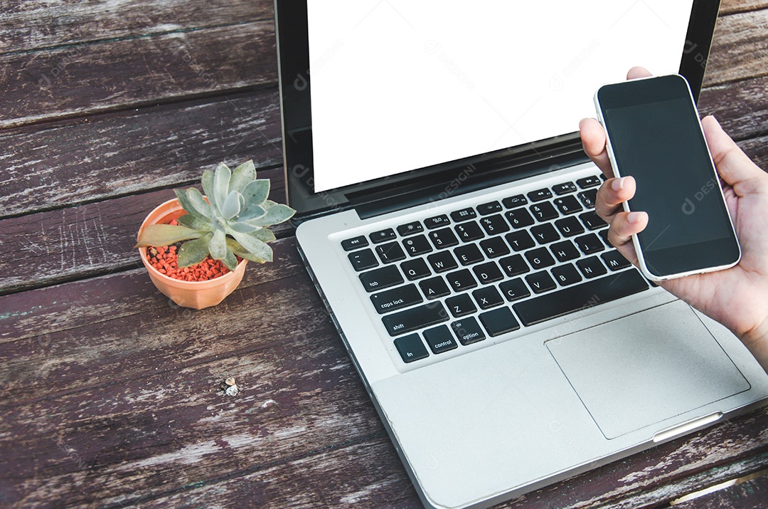 Mãos femininas segurando celular e computador laptop