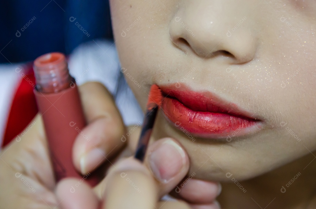 As crianças asiáticas estão aplicando batom vermelho