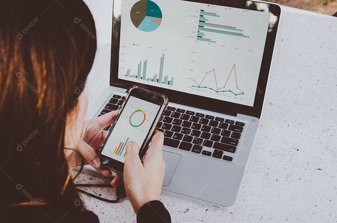 Empresária trabalhando sentado ao ar livre laptop e smartphone com gráficos, diagramas e gráficos na tela.