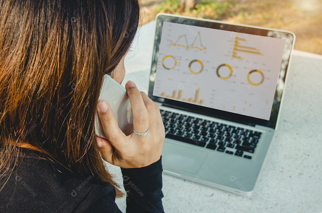 Businesswoman working sitting outdoors laptop and smartphone with charts, diagrams and charts on screen.