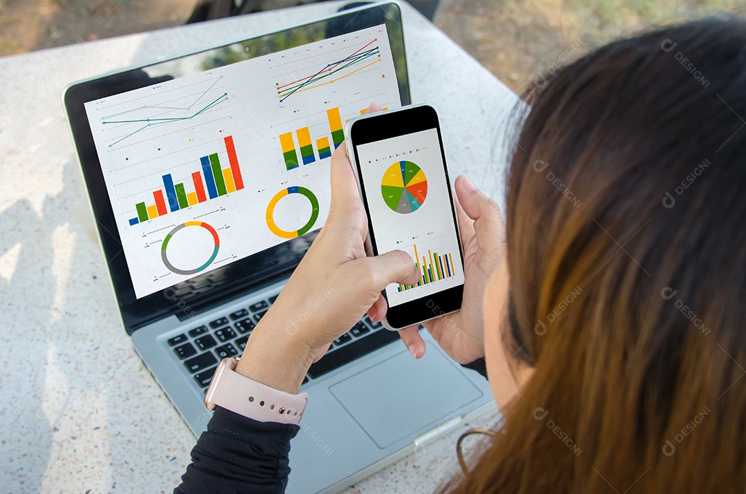 Empresária trabalhando sentado ao ar livre laptop e smartphone com gráficos, diagramas e gráficos na tela.
