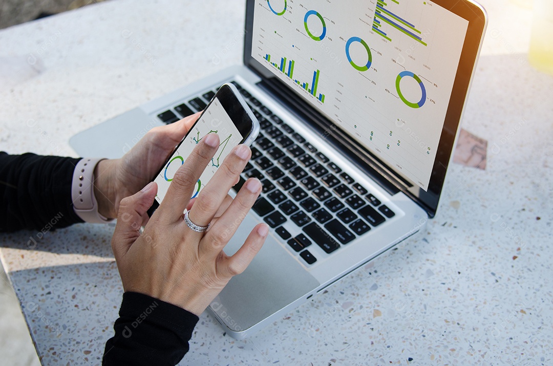 Empresária trabalhando sentado ao ar livre laptop e smartphone com gráficos, diagramas e gráficos na tela.