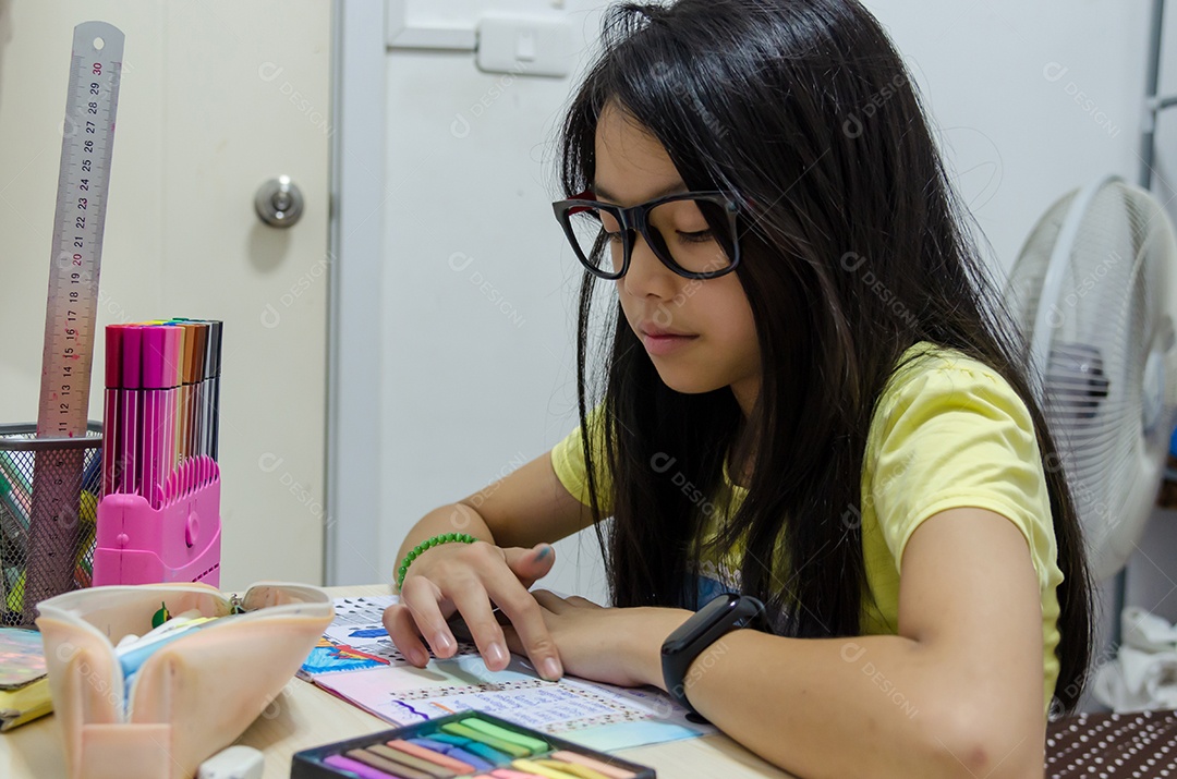 Menina asiática está fazendo lição de casa em casa.