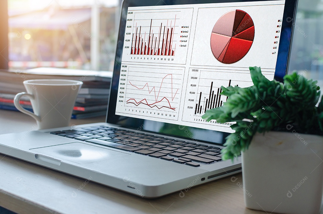 Laptop e smartphone com gráficos, diagramas e tabelas na tela na mesa de madeira.
