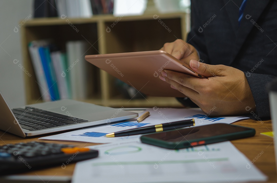 Empresário de pessoa segurando o gráfico de análise de tecnologia de comunicação digital tablet e gráfico de finanças na mesa.