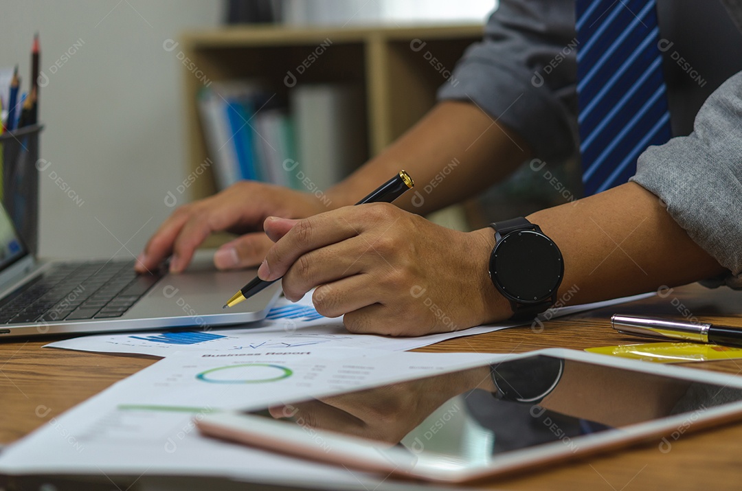 Empresário segurando o gráfico de documento de caneta contabilidade finanças papel análise gráfico investimento de marketing e economia de relatório com computador portátil na mesa no escritório.