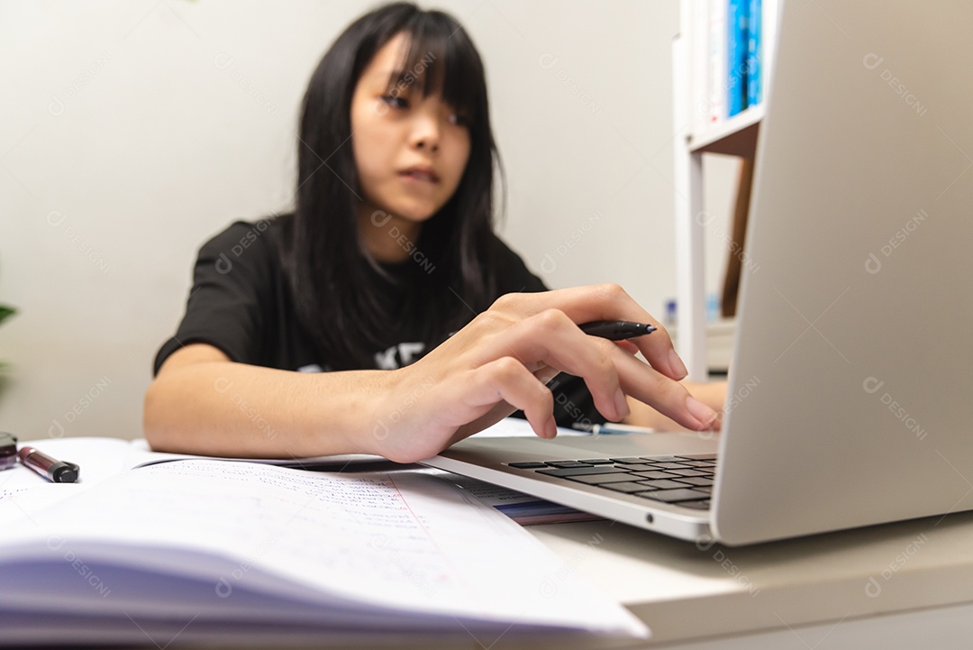 Menina adolescente asiática usa computador laptop tecnologia internet pesquisa on-line informações rede social e educação lição de casa na mesa.