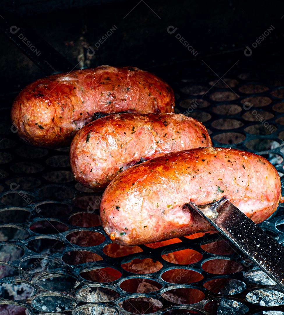 Churrasco sendo preparado na churrasqueira com carvão e fogo quente. linguiça de porco assada no espeto.