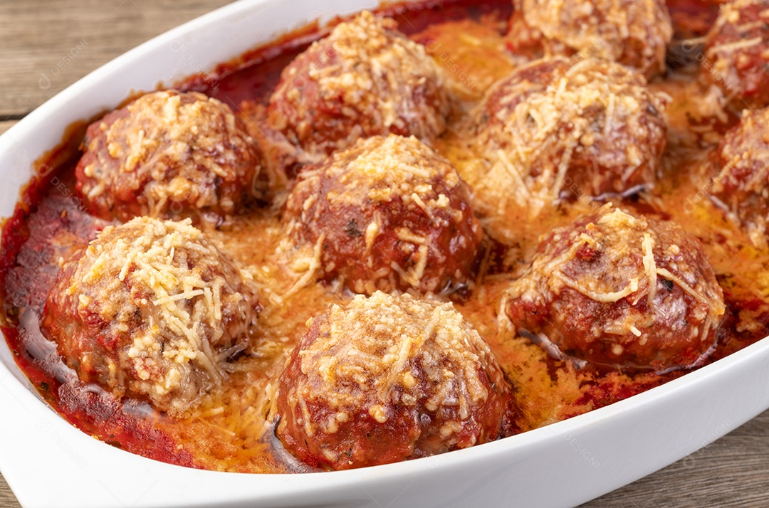 Bolas de carne em um prato branco com molho de tomate e queijo derretido.