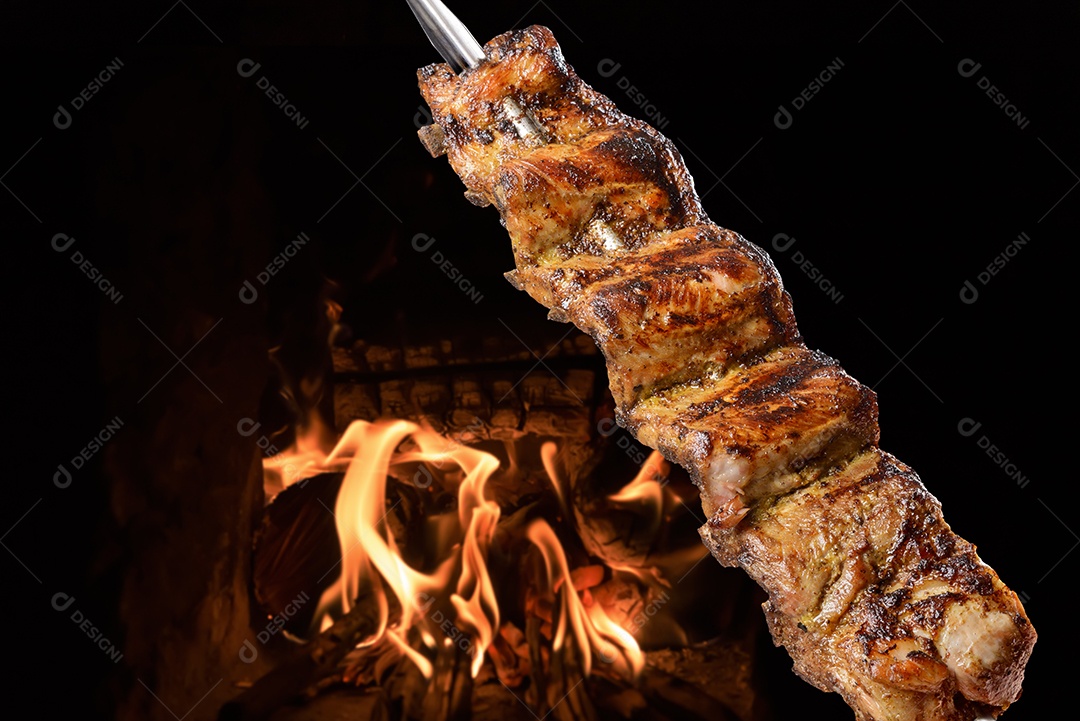 Costelinha de porco assada no espeto com fogo ao fundo. comida brasileira.