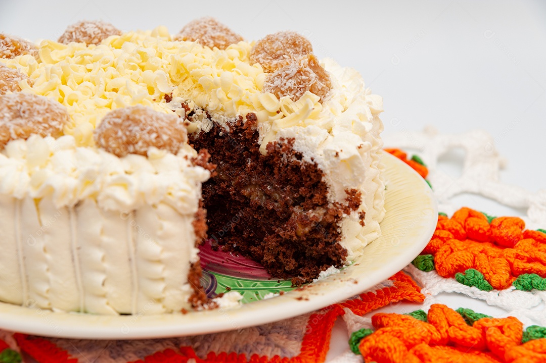 Delicioso bolo de chocolate recheado caseiro decorado com chocolate branco ralado e trufas de doce de leite de coco. Fundo de toalha de crochê