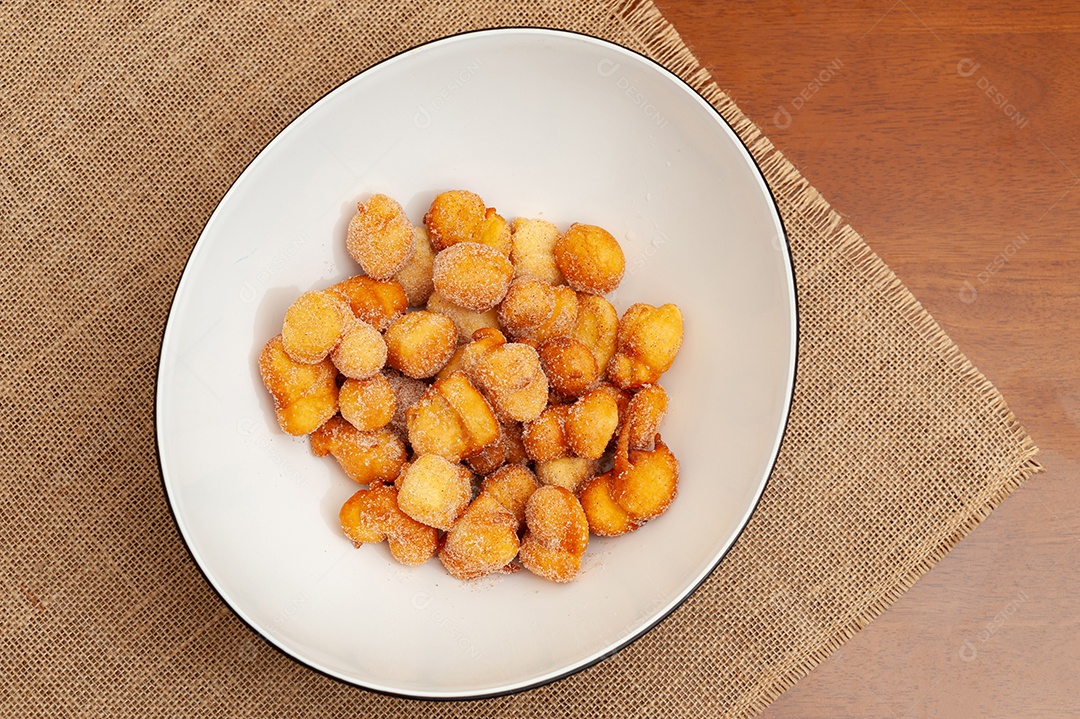 Delicious and traditional homemade Brazilian sweet called Bolinho de Chuva on a plate. Isolated on wooden background. Top view. copy space