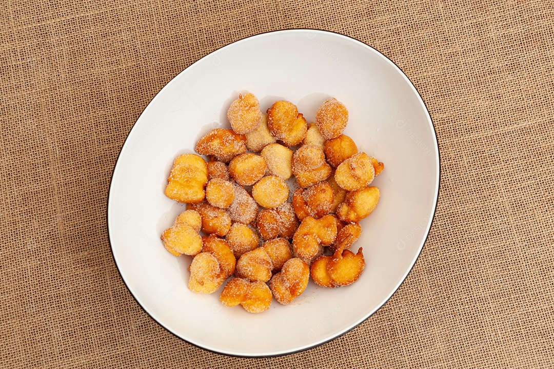 Delicioso e tradicional doce brasileiro caseiro chamado Bolinho de Chuva em um prato. Isolado em fundo de madeira. Vista do topo. Copiar espaço
