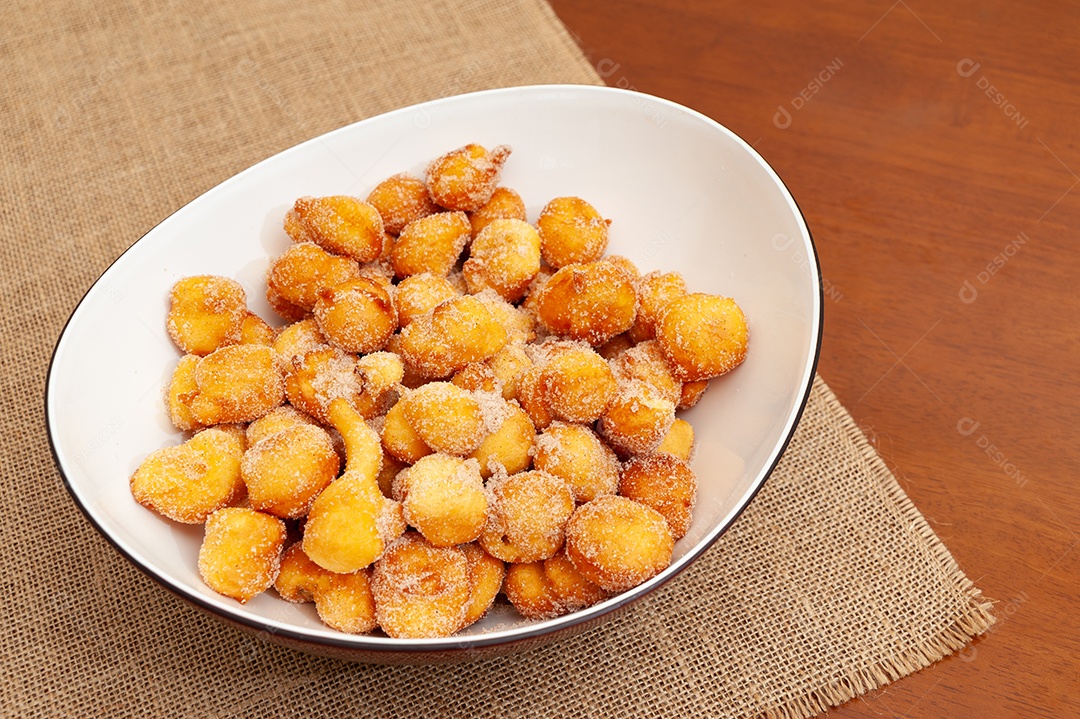 Delicioso e tradicional doce brasileiro caseiro chamado Bolinho de Chuva em um prato. Isolado em fundo de madeira. Vista do topo. Copiar espaço