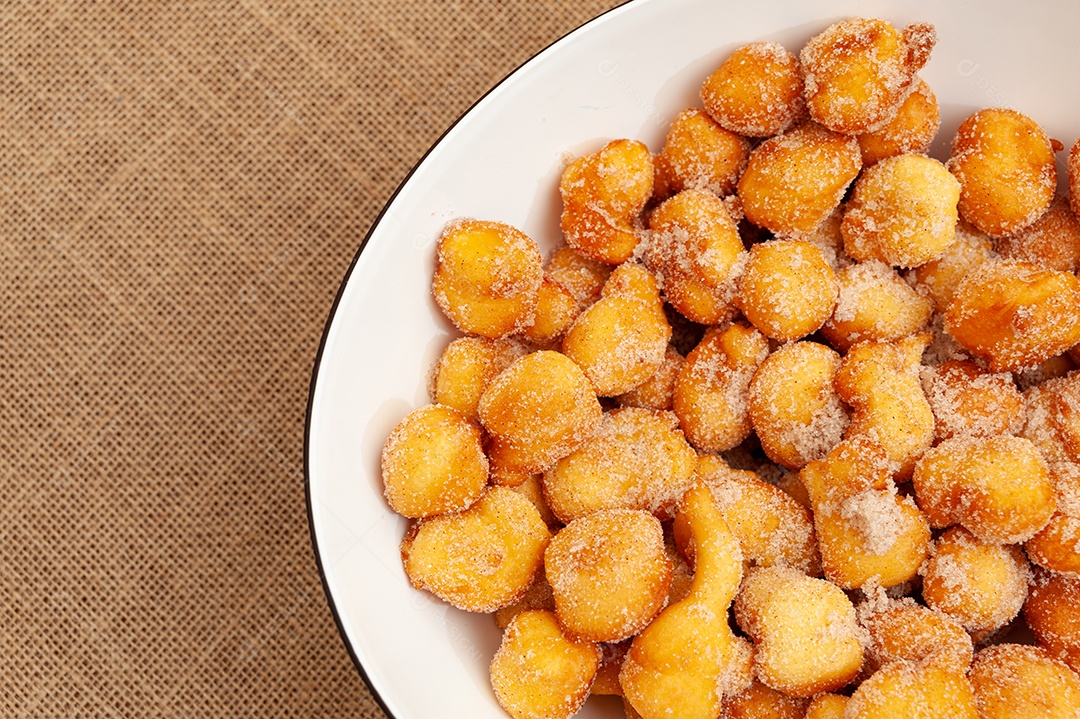 Delicioso e tradicional doce brasileiro caseiro chamado Bolinho de Chuva em um prato. Isolado em fundo de madeira. Vista do topo. Copiar espaço